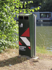 902590 Afbeelding van een afvalbak met de opdruk 'Business Eiland Utrecht', op de oever van de Vaartsche Rijn bij de ...